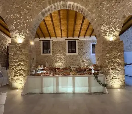 Un arco in pietra della sala illuminato, con il buffet sotto